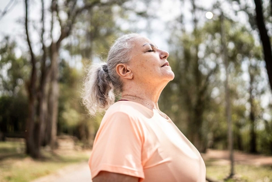 A woman taking a deep breath while going on a walk in nature