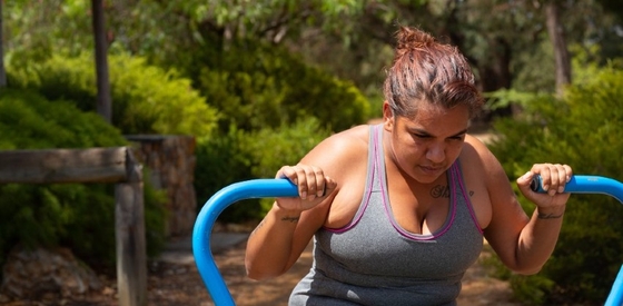 Young First Nations woman holding climbing rails at a pool 