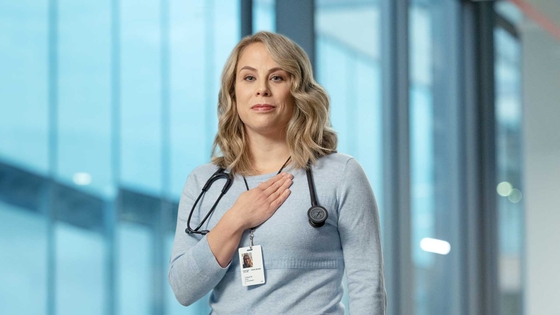 Dr Clare Arnott in a clinical setting with her hand on her heart