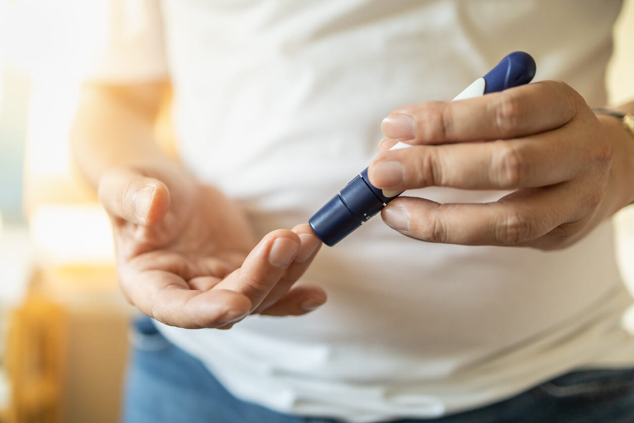 A person holding a blood glucose meter, measuring their blood sugar levels for diabetes management.