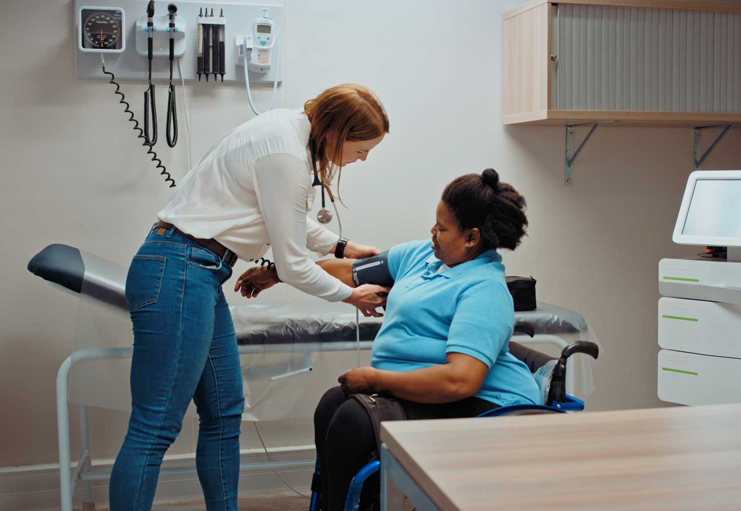 Healthcare worker checking blood pressure of a patient in a wheelchair
