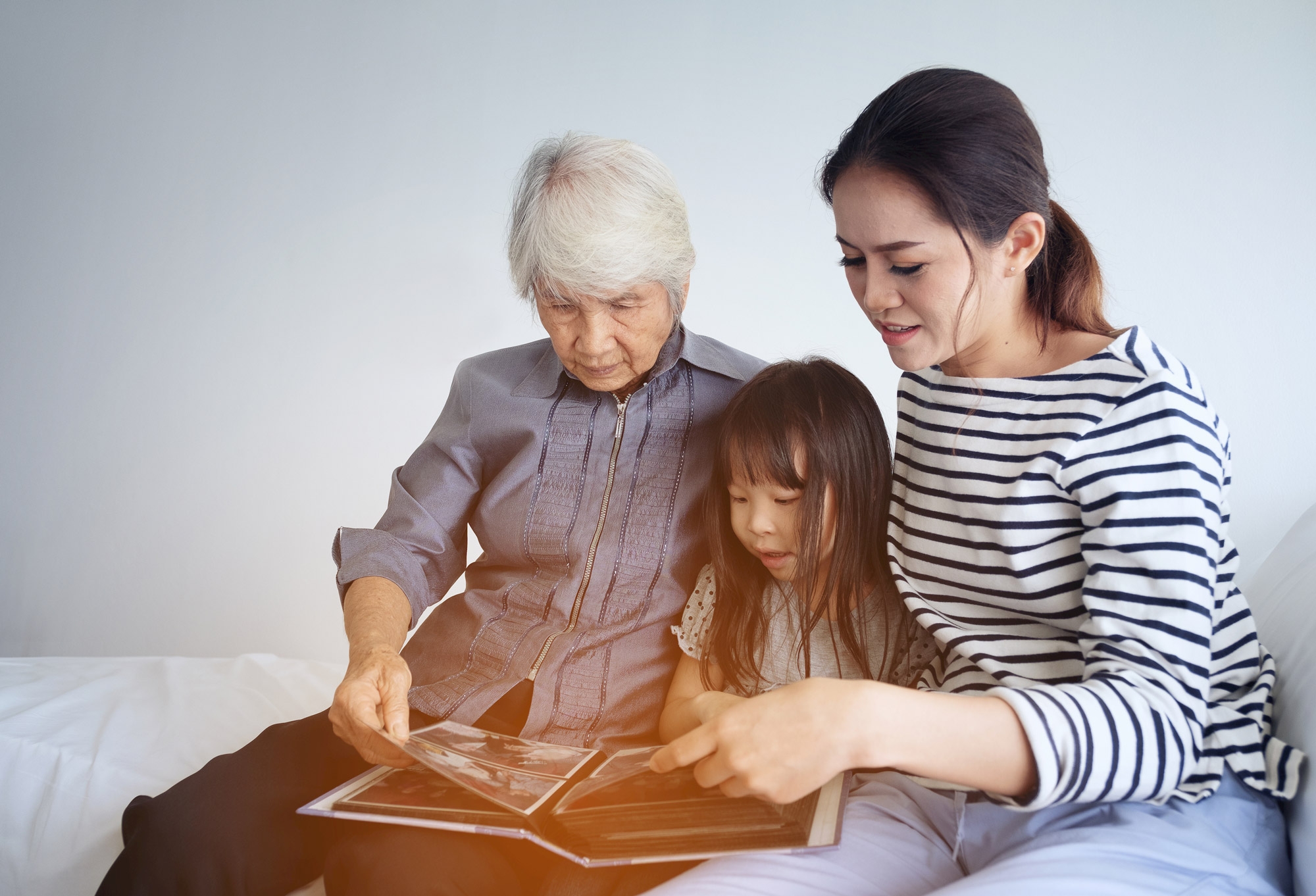Three generations of women, older grandma (mother), mother and young daughter looking at photo album