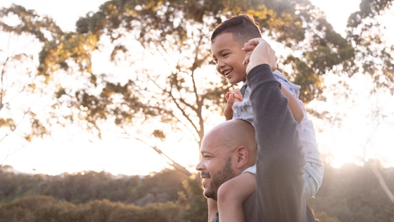 A man holding his smiling son up on his shoulders