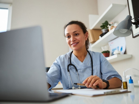 Woman watching a laptop screen while stretching her hand and typing on it