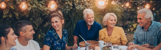 Happy group of people sitting together, outdoor dinner party, hosting an event