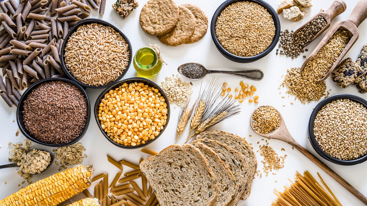 A collection of different grains and cereals displayed in bowls and spoons.